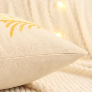 Close-up detail of beige canvas cushion cover featuring elegant gold embroidery pattern.