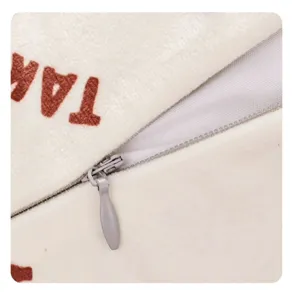 Soft plush cushion cover detail featuring smooth hidden zipper and brown letter print.
