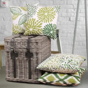 Detailed view of green and white botanical floral cushion covers in a cozy room setting.