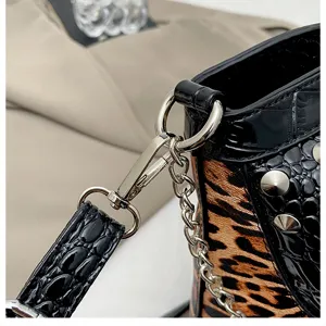 Close-up of stylish handbag hardware, leopard print texture, metal chain and stud details.