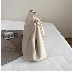 Detailed shot of beige canvas tote bag, spacious minimalist shoulder bag for casual daily use.