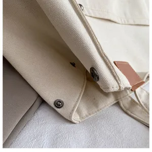 Close-up view of casual canvas tote bag showing metal snap closure and fine stitching details.