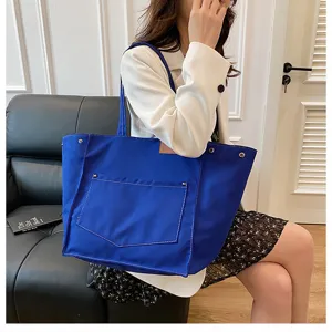 Close-up detail of a stylish blue canvas tote bag with front pocket, perfect for daily casual wear.