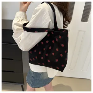 Ribfluwelen aardbei print tote bag detailweergave met zwarte stof en patroon.