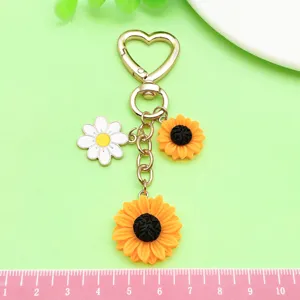 Detailaufnahme des Sonnenblumen- und Gänseblümchen-Schlüsselanhängers mit schönem Herzkarabiner.