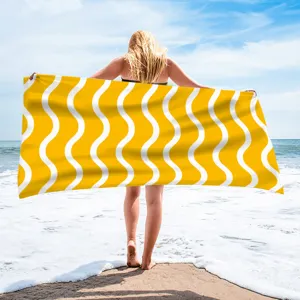 Detailed view of yellow and white wavy print beach towel showcased in outdoor beach scene.