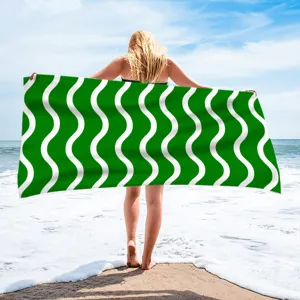 Detailed view of quick-dry polyester beach towel with green and white wavy pattern for swim.