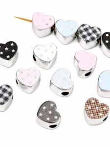 Detailed close-up of silver plated acrylic heart beads with star and plaid prints for DIY crafts.