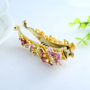 Detailed view of gold-tone metal banana hair clip featuring enamel painted flowers and sparkling rhinestones.