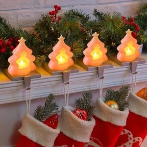 Detailansicht rosafarbener Weihnachtsbaum LED Kerzenlichter am Kaminsims mit festlicher Deko.