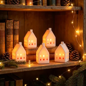 White ceramic house LED candle light with warm glowing lights, exquisite desktop holiday decor detail.