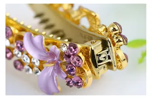 Detailed close-up of a gold metal hair claw clip adorned with purple enamel and rhinestones.
