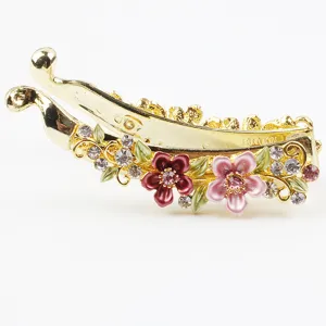 Gold-tone metal banana hair clip featuring colorful enamel flowers and sparkling rhinestones.