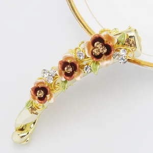 Elegant alloy banana hair clip decorated with enameled flowers, green leaves and rhinestones.