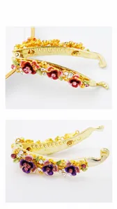 Detailed view of gold tone metal banana hair clip featuring colorful enamel flowers and clear crystals.