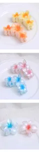 Closeup of colorful resin plumeria flower hair claws, beautiful gradient tones, detailed design.