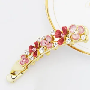 Detailed view of gold-tone banana hair clip with enamel pink flowers and sparkling crystals.