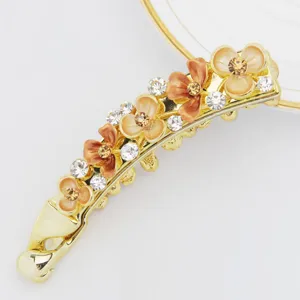 Detail shot of a Korean style flower banana hair clip, gold metal with enamel and rhinestones.