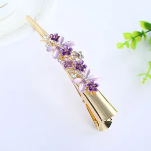 Gold alloy hair clip detail featuring purple enamel flowers and sparkling rhinestones.