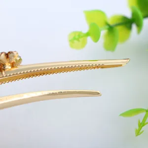 Close-up detail of golden metal hair clip with serrated teeth design and elegant finish.