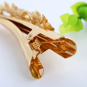 Close-up view of a luxury gold metal hair clip, showing the delicate leaf hollow spring clip design.