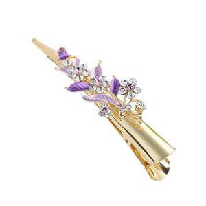 Close-up of gold hairpin with purple enamel leaves and sparkling rhinestones for elegant hairstyles.