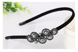Detailed shot of a black velvet headband decorated with blue rhinestones and grey pearls.