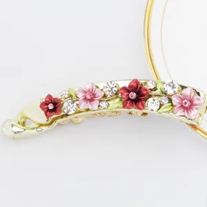 Nahaufnahme einer goldenen Bananenhaarspange aus Legierung mit rosa Blumen und Strasssteinen.