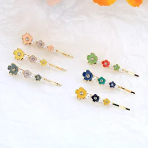 Detailed shot of sweet enamel flower hair clips with rhinestones and pearls on crinkled paper.