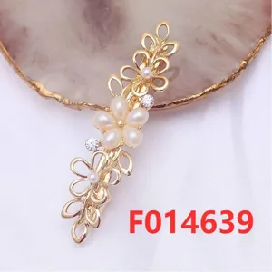 Gold metal flower hair clip detail, featuring pearl and rhinestones for elegant styling.