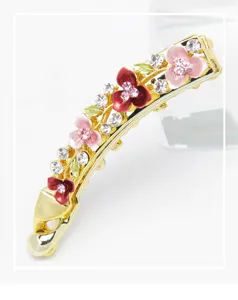 Detalle de pinza para el pelo floral de aleación dorada con flores esmaltadas y brillantes.