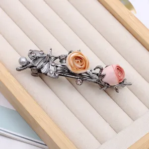 Élégante pince à cheveux ressort en tissu rose, design de branches en métal foncé.