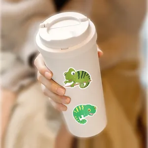 Close-up detail shot of cute cartoon lizard stickers displayed on a clean white travel cup.