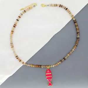 Gros plan sur le collier de perles colorées avec pendentif poisson émail rose, détails.
