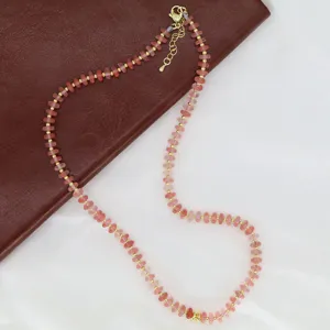 Gros plan détaillé du collier de perles roses avec des perles d'espacement dorées sur tissu.