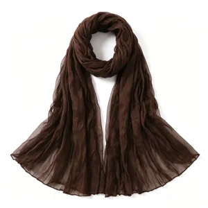 Gros plan sur le tissu froissé en coton et lin de l'écharpe marron, détails et texture de qualité.