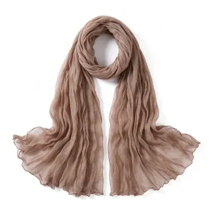 Gros plan sur la texture légère, respirante et froissée du foulard uni et son drapé élégant.