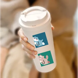 Close-up detail of white travel mug featuring cute cartoon animal stickers held in hand securely.