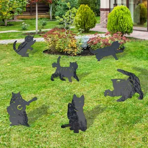Dettaglio di simpatici paletti da giardino con silhouette di gatto nero sul prato verde.