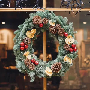 Detailed view of handmade Christmas wreath with pine cones and dried orange slices decor.