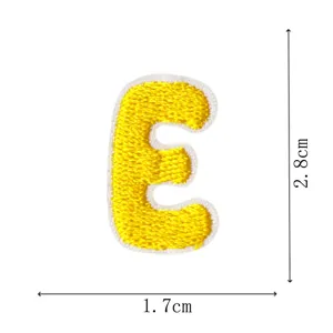 Detailed view of yellow embroidered letter E patch with size markers, DIY clothing accessory.
