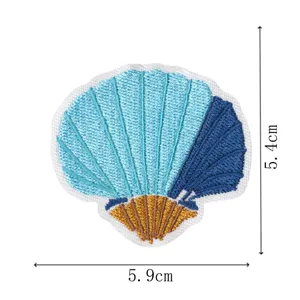 Blue and gold embroidered seashell patch detail showing fine stitching texture and size info.