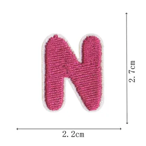 Close-up detail shot of a pink embroidered letter N patch with white border, showing texture.