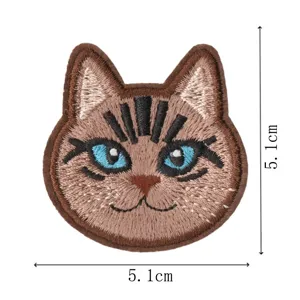 Cute cartoon cat head embroidery patch close up, brown fabric iron on applique for clothes repair.