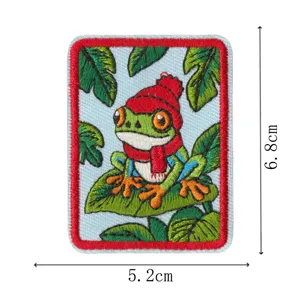 Detailaufnahme des süßen bestickten Frosch-Flickens mit Mütze, feine Handwerkskunst.