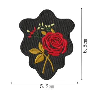 Vue détaillée de patch brodé rose rouge, tissu noir avec feuilles dorées, 6.6x5.2cm.