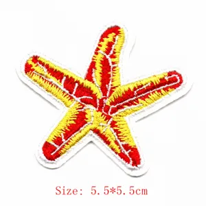 Gros plan détail du patch brodé d'étoile de mer jaune et rouge, texture de couture.