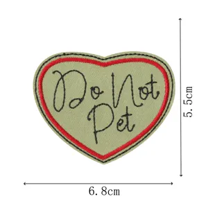 Heart-shaped embroidered patch detail showing the black lettering and red border clearly.