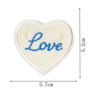 Nahaufnahme des weißen herzförmigen bestickten Aufnähers mit blauem Love-Schriftzug in 5.7x5cm.