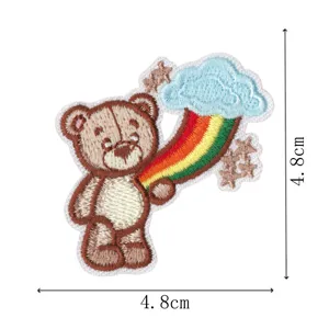 Close-up of cute cartoon teddy bear and rainbow cloud embroidered patch detail, fine craft.